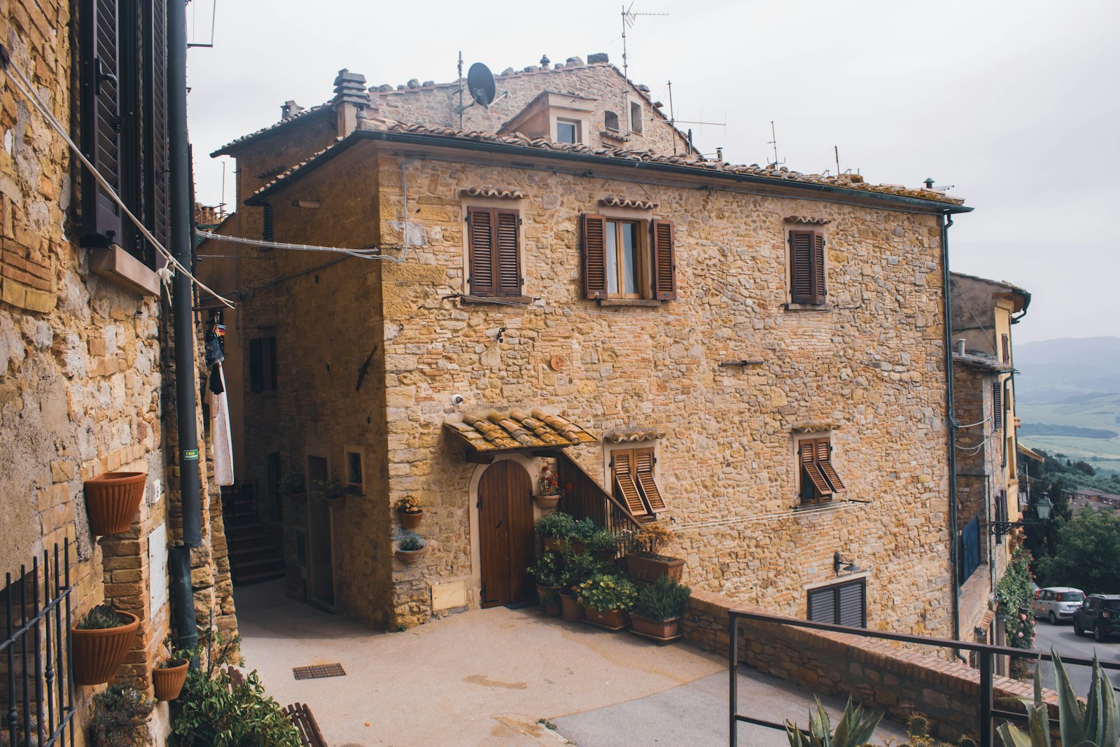 Steinhaus an einer abschüssigen Gasse mit Holztür und Topfpflanzen davor