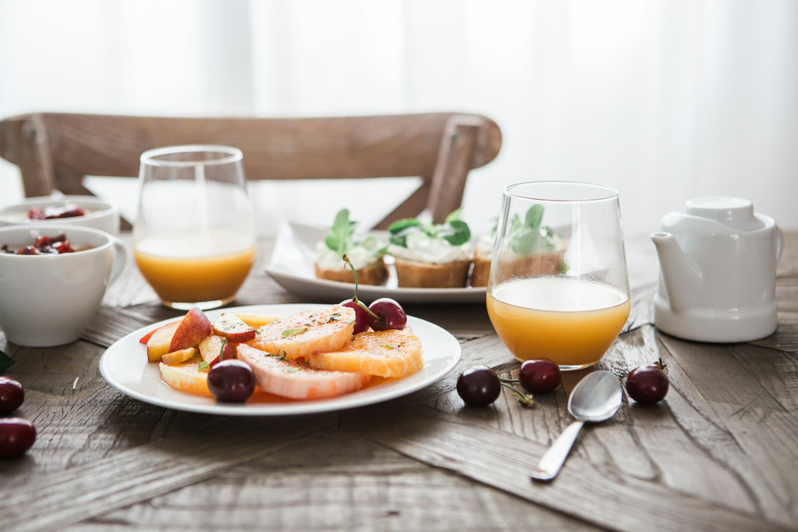 Gedeckter Frühstückstisch mit Obst, Gebäck und Saft auf Holz