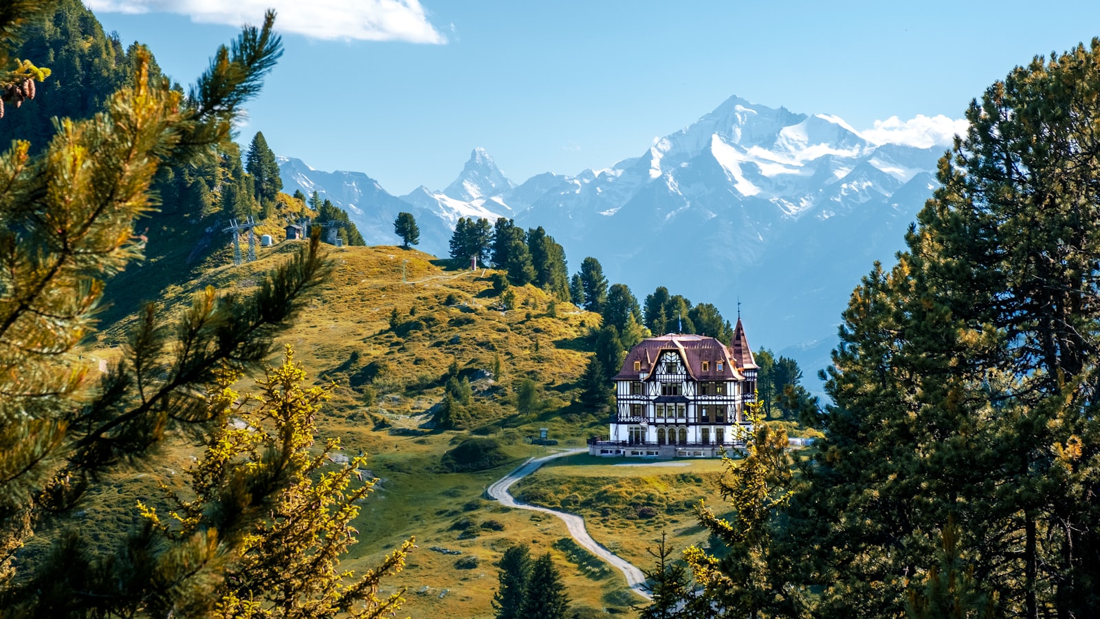 Das Landhotel Kranzhof auf einer Wiese oberhalb des Dorfes, dahinter Wald und Berge