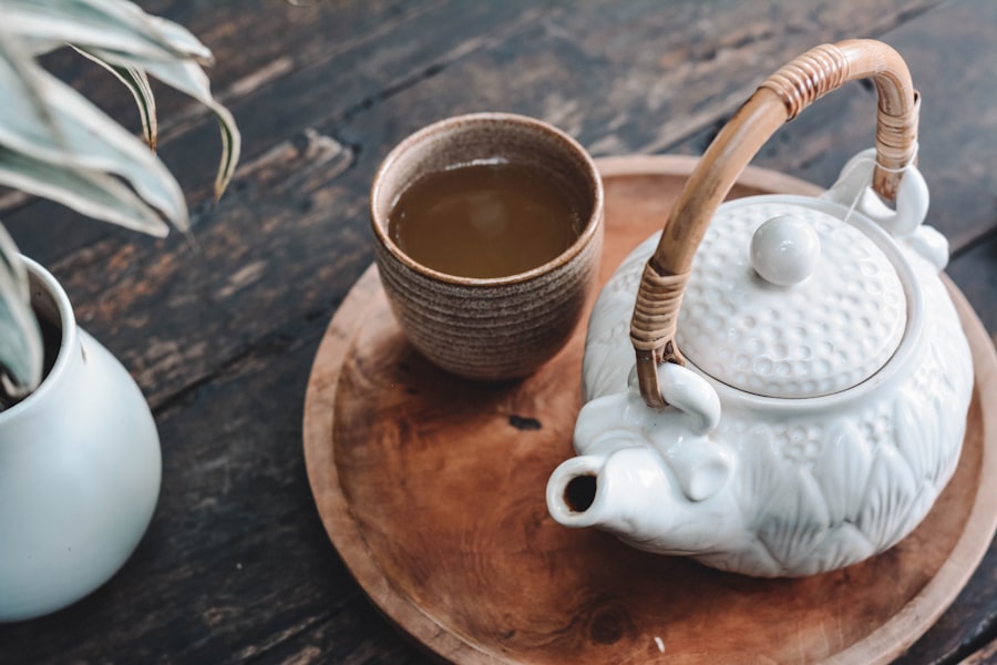 Teekanne und Tasse mit grünem Tee auf einem Holztablett