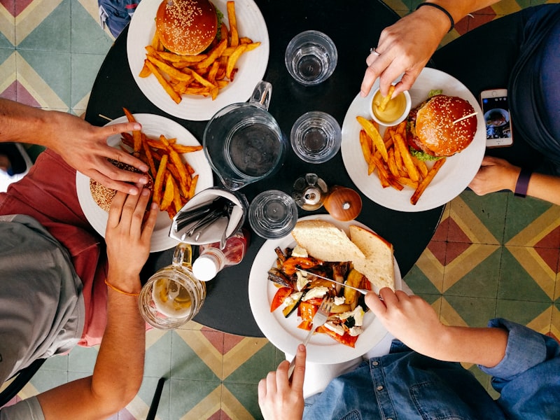 Burger, Pommes und Getränke werden auf einem Tisch geteilt