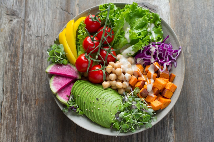 Schale mit Avocado, Kichererbsen, Süßkartoffel, Rotkohl und Radieschen auf einem Holztisch