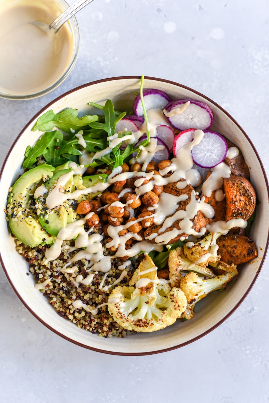 Bowl mit Quinoa, Blumenkohl, gerösteten Kichererbsen, Avocado und Tahini