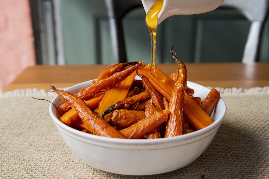 Ofenmöhren in einer weißen Schale, eine helle Sauce wird darübergegossen